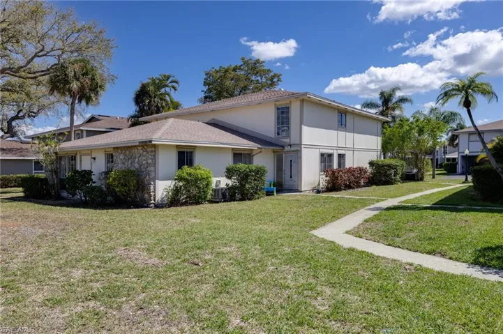 View of side of property with a lawn and stone siding