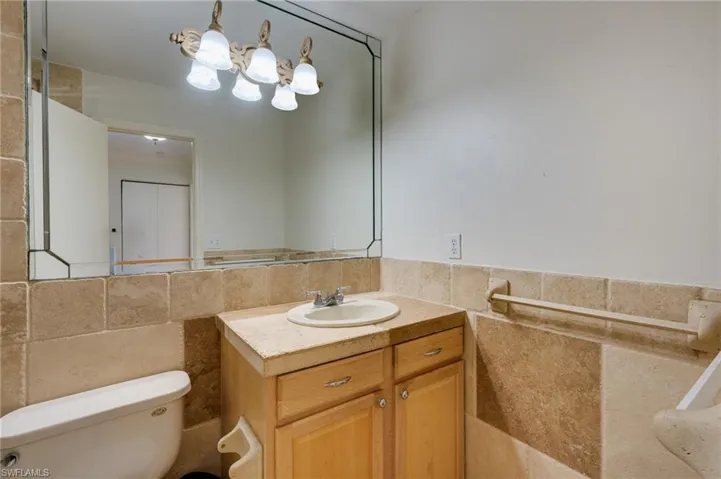 Bathroom vanity featuring a light wood-finish cabinet with double doors, an integrated sink, a coordinated countertop, and a large wall-mounted mirror