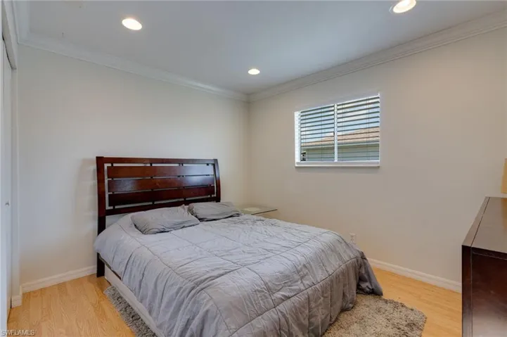 Bright room featuring wood-finish flooring, recessed lighting, white walls, and crown molding