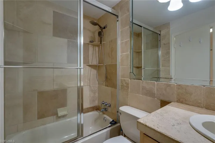 Bathroom featuring a tiled shower and bathtub combination with a glass enclosure