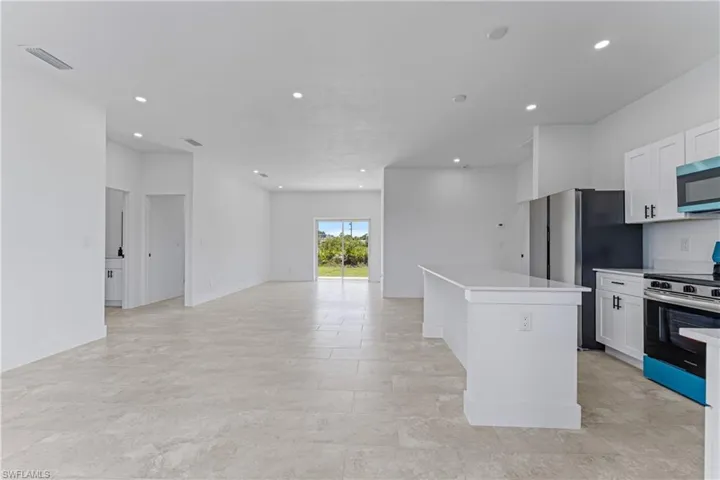 Kitchen with stainless steel appliances, white cabinetry, recessed lighting, a kitchen island, and open floor plan