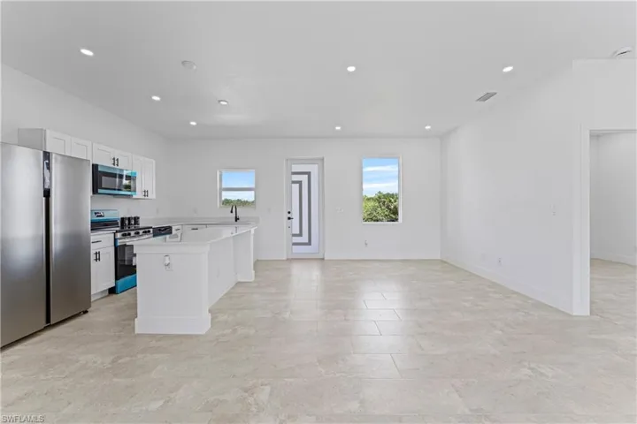 Kitchen featuring stainless steel appliances, a kitchen island, white cabinetry, recessed lighting, and open floor plan