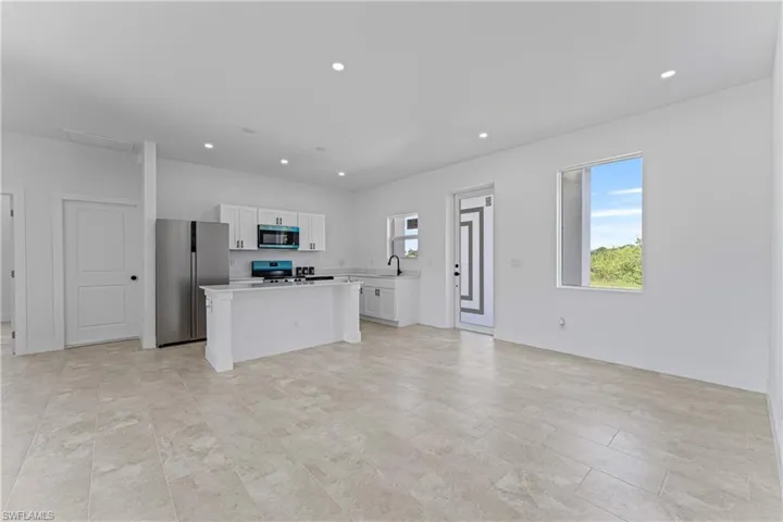 Kitchen featuring white cabinetry, appliances with stainless steel finishes, recessed lighting, light countertops, and a kitchen island