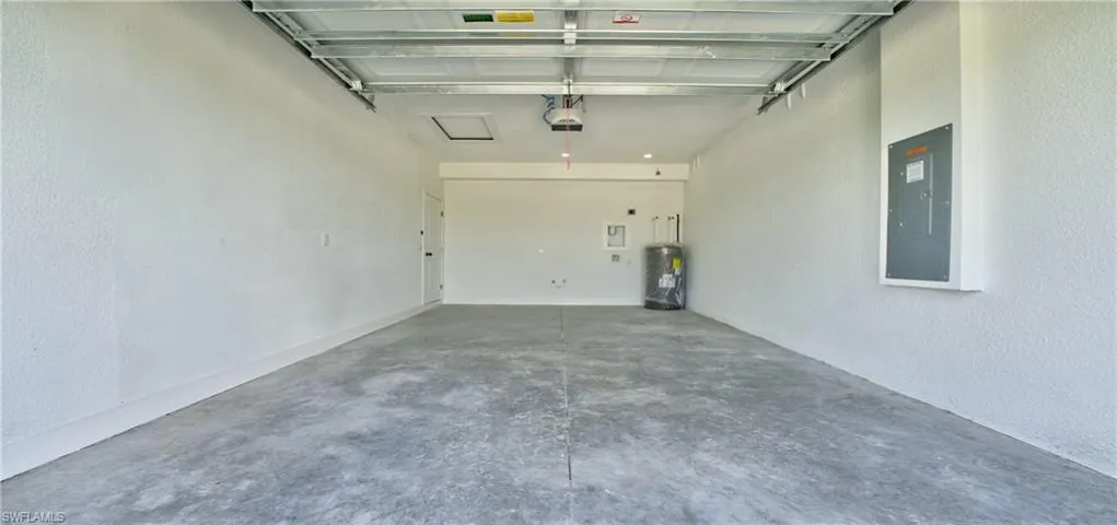 Garage featuring a textured wall, electric panel, and water heater
