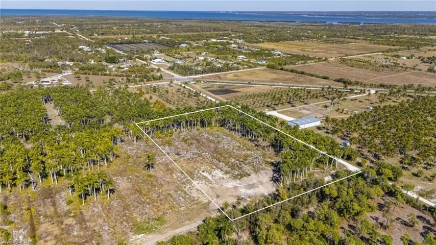 View of rural area featuring property parcel outlined, rows of crops, and a large body of water