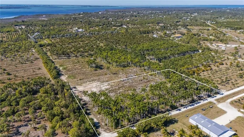 Aerial view of sparsely populated area featuring property parcel outlined and a large body of water