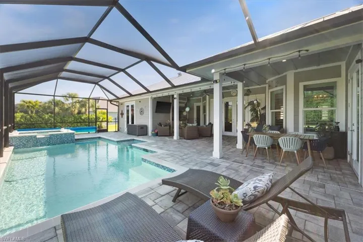 View of pool with a pool with connected hot tub, an outdoor hangout area, a lanai, and a patio