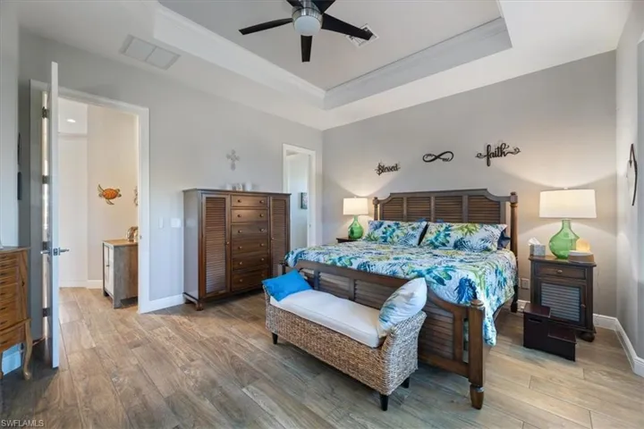 Bedroom with visible vents, a tray ceiling, light wood-style flooring, and ornamental molding