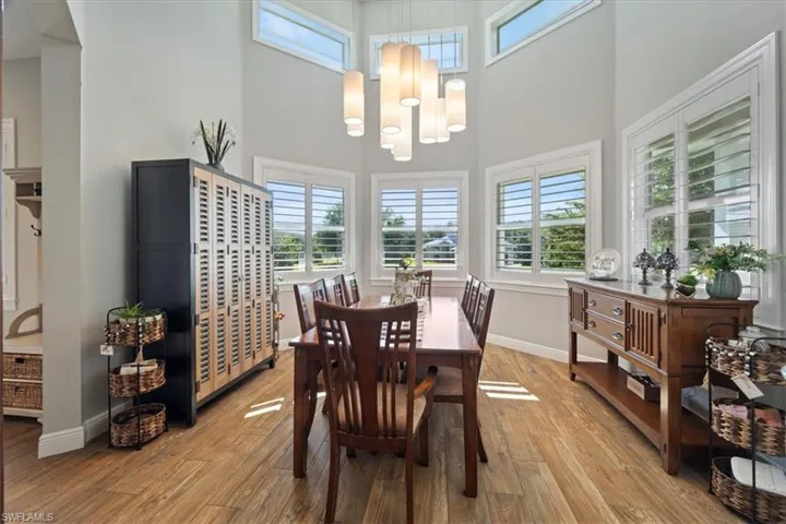 Dining space featuring baseboards, a high ceiling, and light wood-type flooring