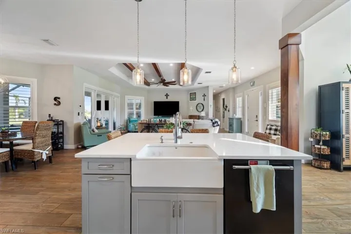 Kitchen featuring open floor plan, light countertops, gray cabinetry, a sink, and light wood-style flooring
