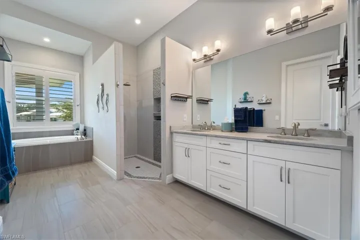 Full bath with a bath, double vanity, a sink, and a shower stall