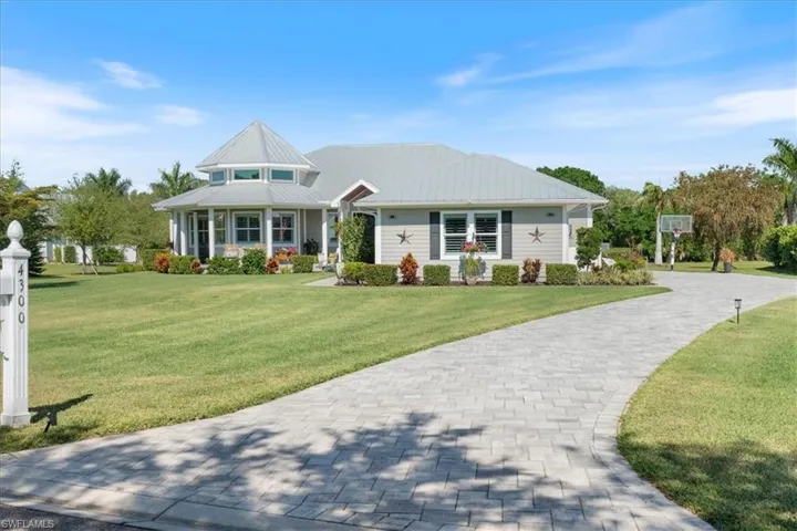 View of front facade with decorative driveway, metal roof, and a front lawn