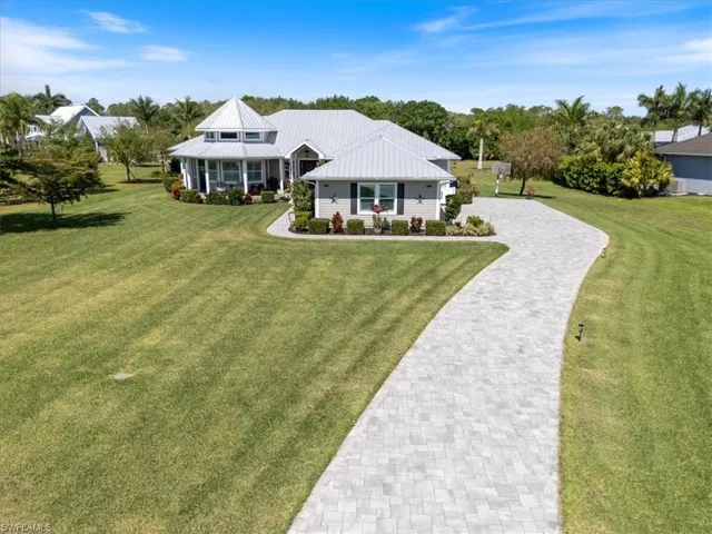 View of front facade featuring a front yard, driveway, and metal roof