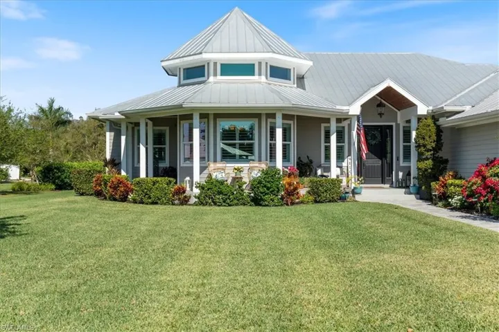 View of front of house with a porch, metal roof, a standing seam roof, and a front lawn