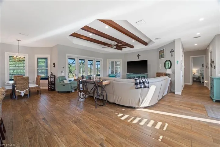 Living area with recessed lighting, ceiling fan with notable chandelier, baseboards, visible vents, and light wood-style flooring