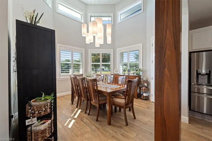 Dining area featuring baseboards, a towering ceiling, light wood-style flooring, and a chandelier