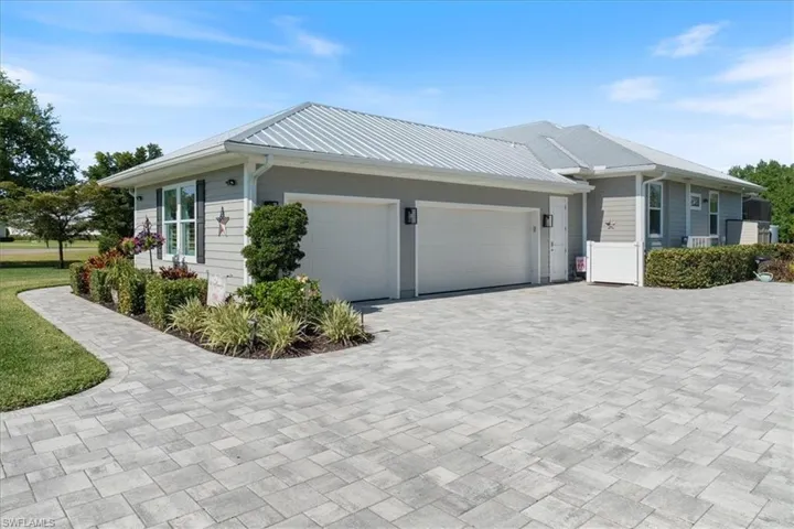 View of side of home featuring decorative driveway, metal roof, and an attached garage