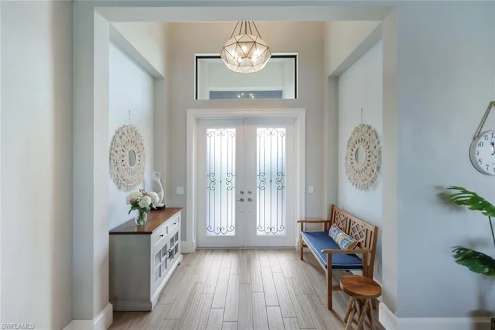 Foyer with light wood-type flooring, a chandelier, and french doors