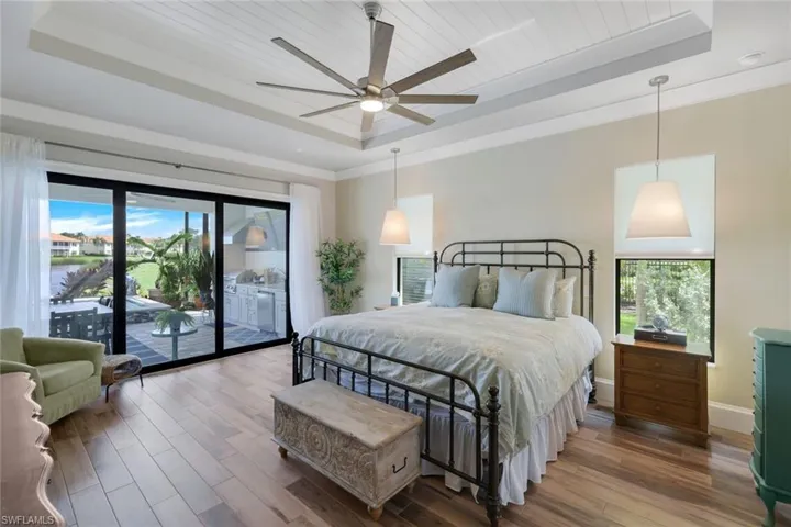 Bedroom with multiple windows, a tray ceiling, ceiling fan, and hardwood / wood-style flooring
