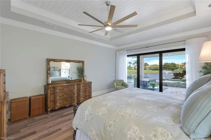 Bedroom featuring a water view, a tray ceiling, ceiling fan, and hardwood / wood-style flooring