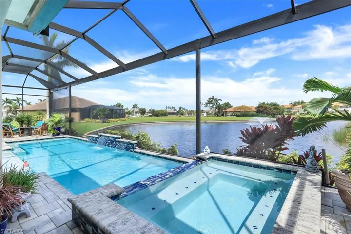 View of pool with a water view, an in ground hot tub, a lanai, a patio area, and pool water feature