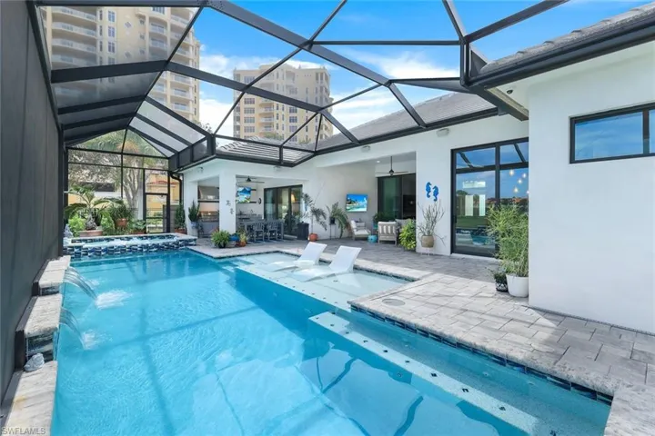 View of pool featuring a patio, pool water feature, an in ground hot tub, glass enclosure, and ceiling fan