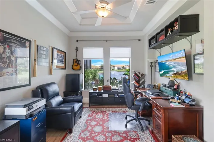 Office space with ceiling fan, light wood-type flooring, and a raised ceiling