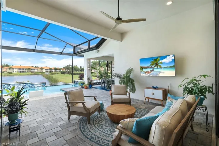 View of patio / terrace featuring a water view, ceiling fan, outdoor lounge area, and glass enclosure