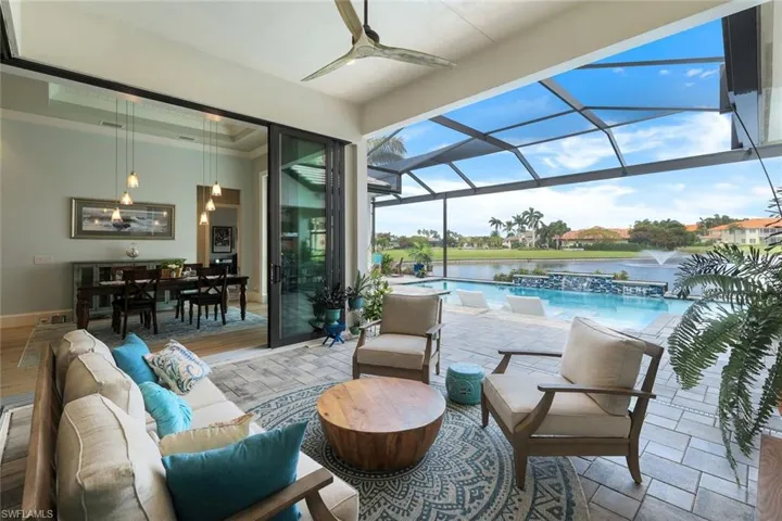 View of patio / terrace with a water view, an outdoor living space, a lanai, ceiling fan, and pool water feature