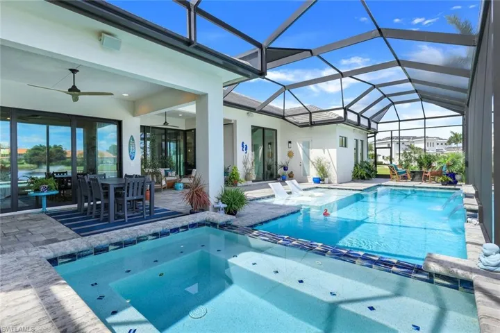 View of swimming pool with ceiling fan, a lanai, an in ground hot tub, and a patio area