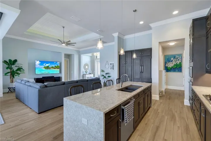 Kitchen featuring hanging light fixtures, light wood-type flooring, ceiling fan, a center island with sink, and sink