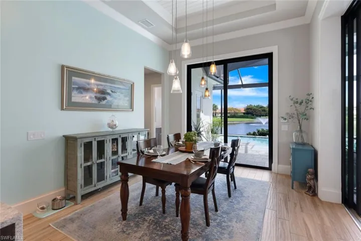 Dining area with a water view, a tray ceiling, and light hardwood / wood-style floors