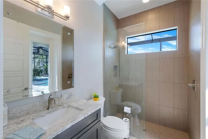 Bathroom featuring vanity, toilet, and tiled shower