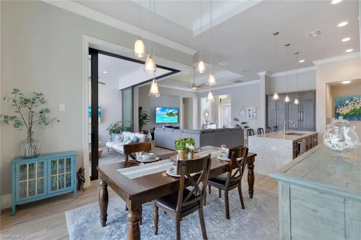 Dining room featuring light wood-type flooring, a tray ceiling, sink, and crown molding