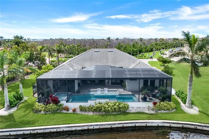 Rear view of property featuring a lawn, glass enclosure, a water view, and a patio area