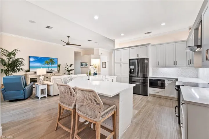 Kitchen featuring stainless steel refrigerator with ice dispenser, light hardwood / wood-style flooring, sink, a kitchen island with sink, and a breakfast bar area