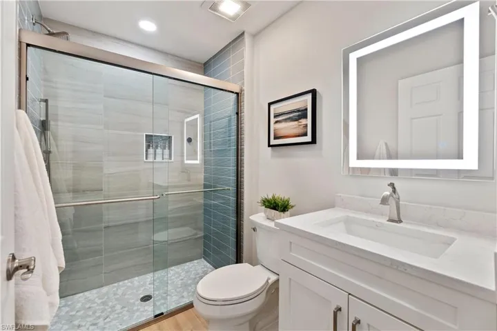 Bathroom featuring hardwood / wood-style flooring, toilet, a shower with door, and vanity