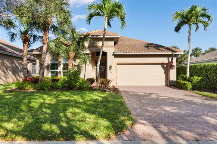 Mediterranean / spanish-style house featuring a tiled roof, an attached garage, decorative driveway, a front lawn, and stucco siding