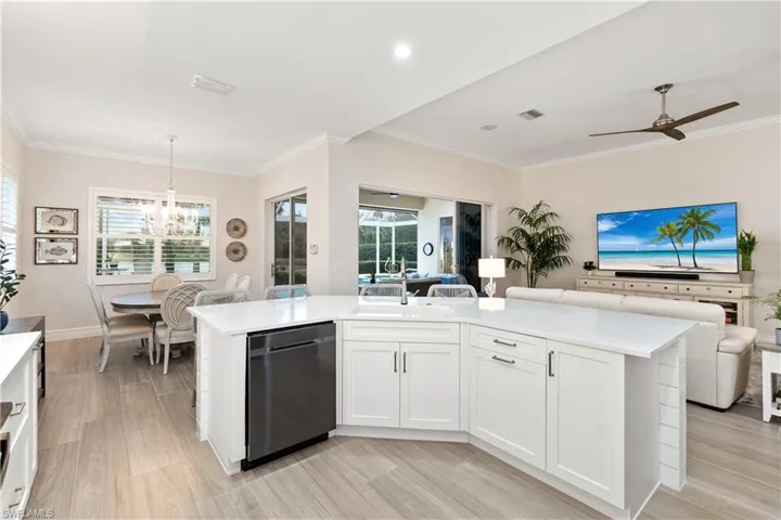 Kitchen with white cabinets, pendant lighting, black dishwasher, and an island with sink