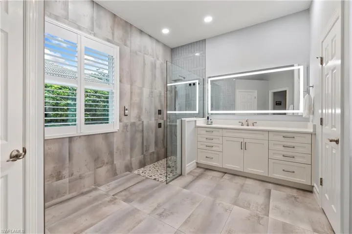 Bathroom with plenty of natural light, tiled shower, and vanity