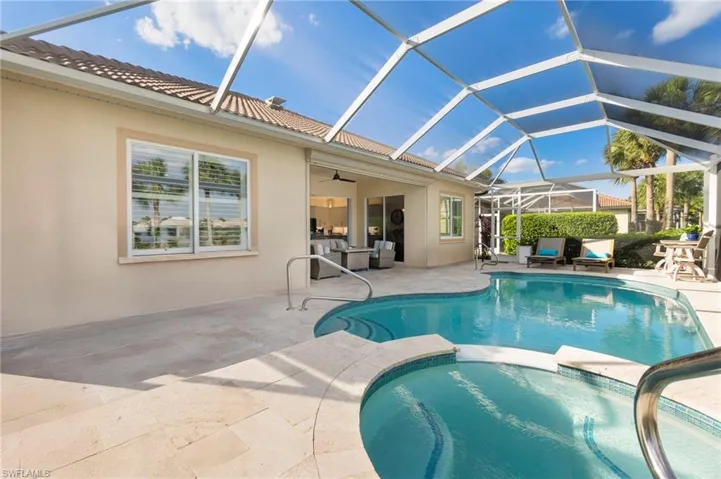 View of swimming pool featuring glass enclosure, a pool with connected hot tub, a patio area, and ceiling fan