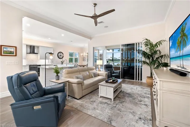 Living room featuring light hardwood / wood-style floors, crown molding, and ceiling fan with notable chandelier