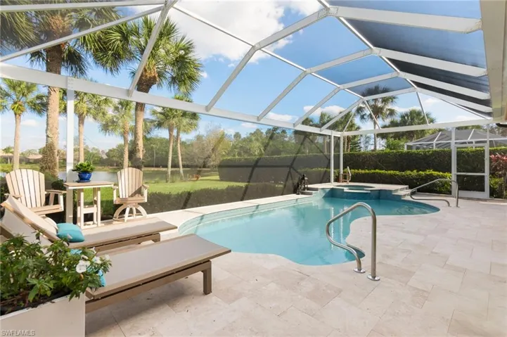 View of swimming pool with a patio, glass enclosure, and a pool with connected hot tub