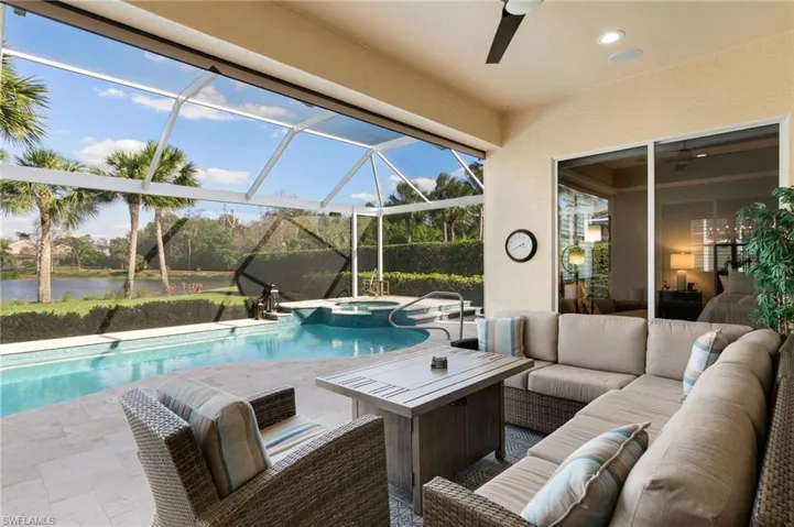 View of swimming pool featuring a water view, a ceiling fan, glass enclosure, a patio area, and an outdoor living space
