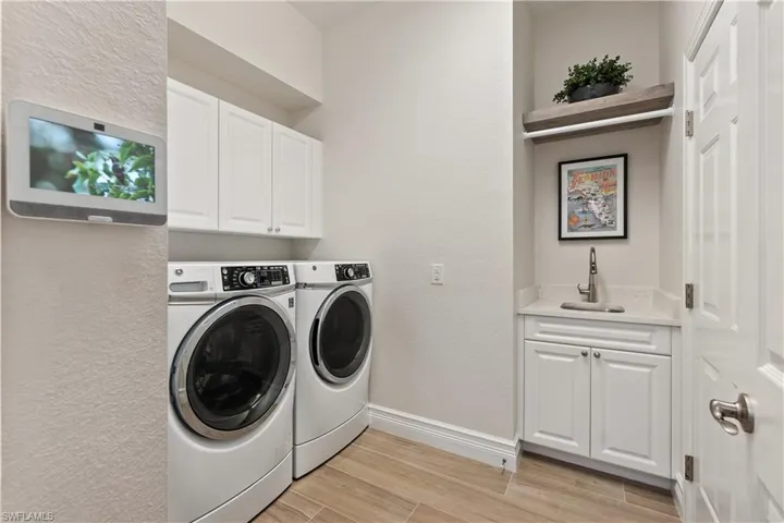 Clothes washing area with cabinets, sink, and separate washer and dryer