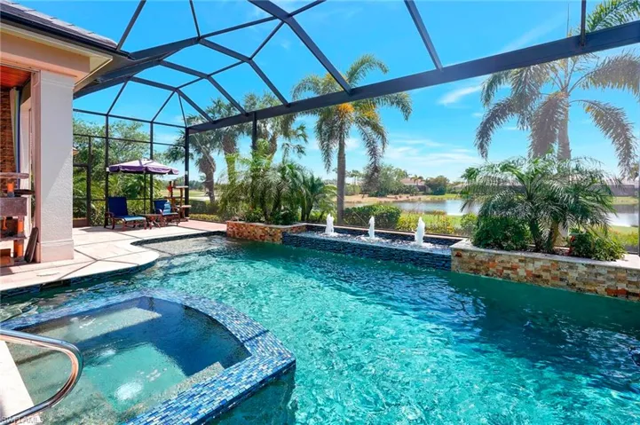 View of swimming pool featuring a pool with connected hot tub, a water view, Screen enclosure, and a spacious lanai