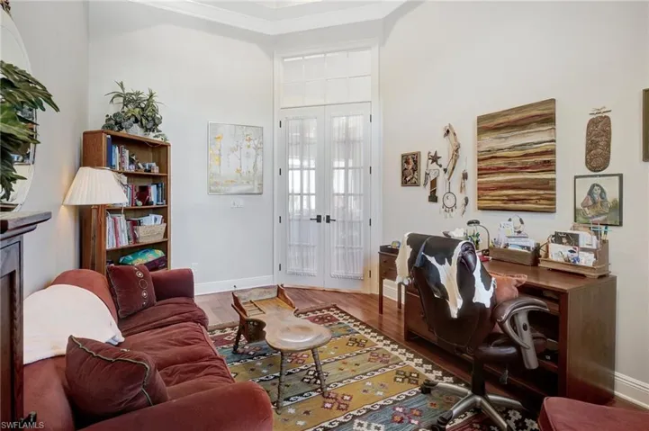 Living area featuring baseboards, crown molding, wood finished floors, and french doors