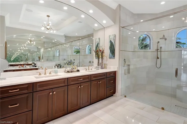 Full bathroom with a shower stall, visible vents, a sink, and a chandelier