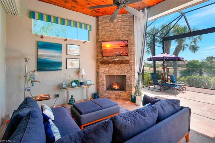 Outdoor lounge area with an outdoor stone fireplace, wood ceiling, a textured wall, and a ceiling fan