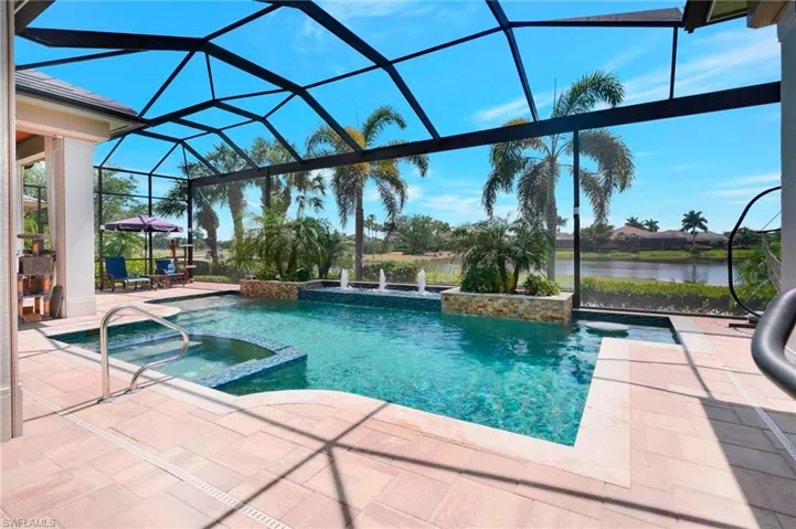 View of swimming pool with glass enclosure, a water view, a pool with connected hot tub, and a patio area